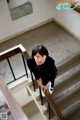 A woman in a school uniform is standing on the stairs.